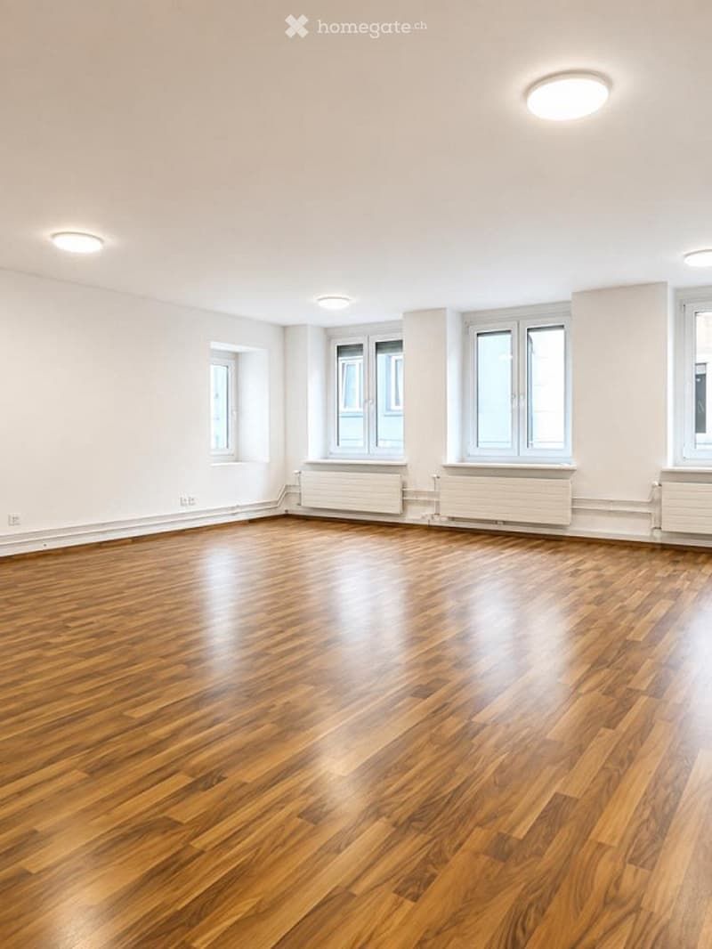 Empty room with wooden flooring, white walls, and multiple windows. No furniture or equipment present.