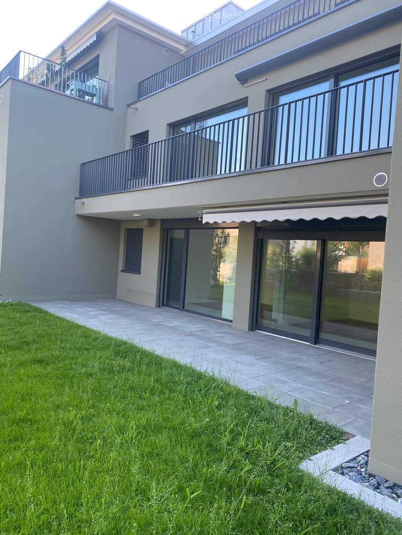 Modern building, beige wall, glass windows, large balconies, awnings