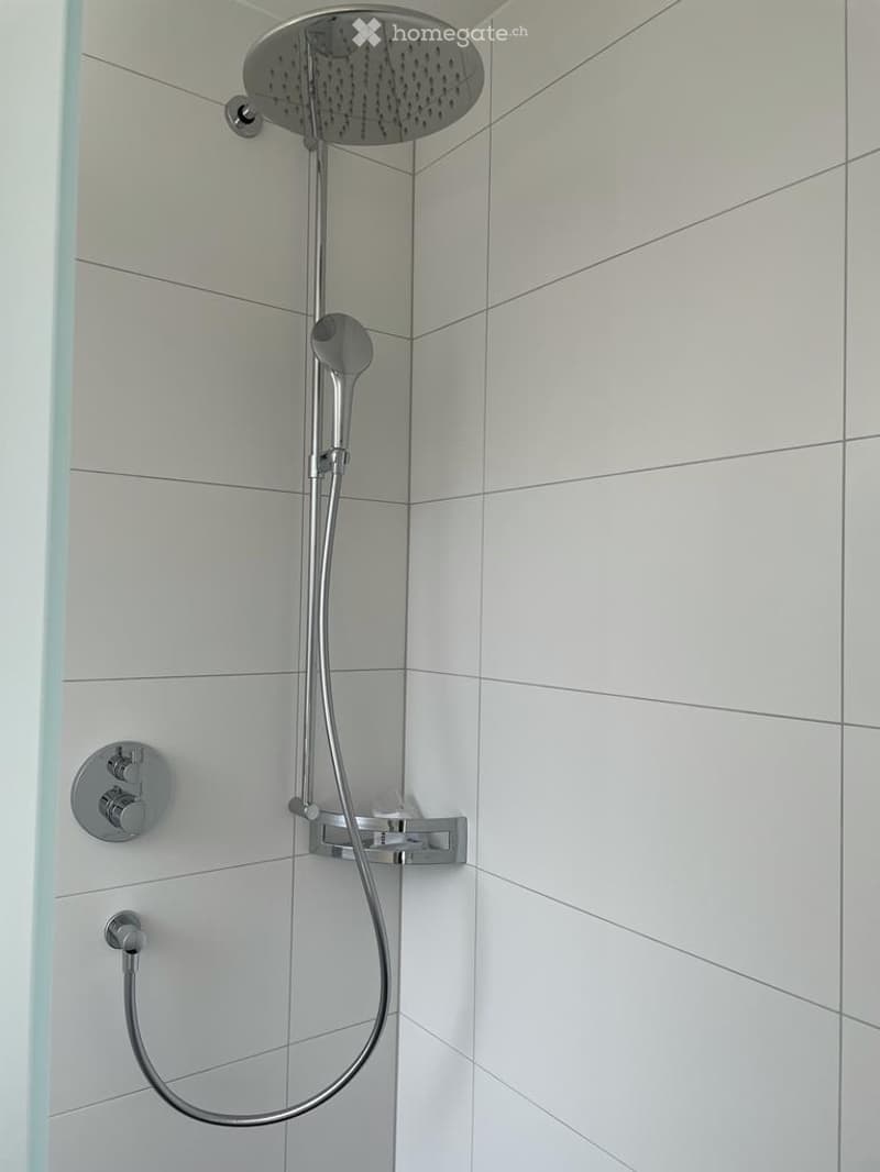 A modern shower with chrome finish and a square head mounted on the wall.
