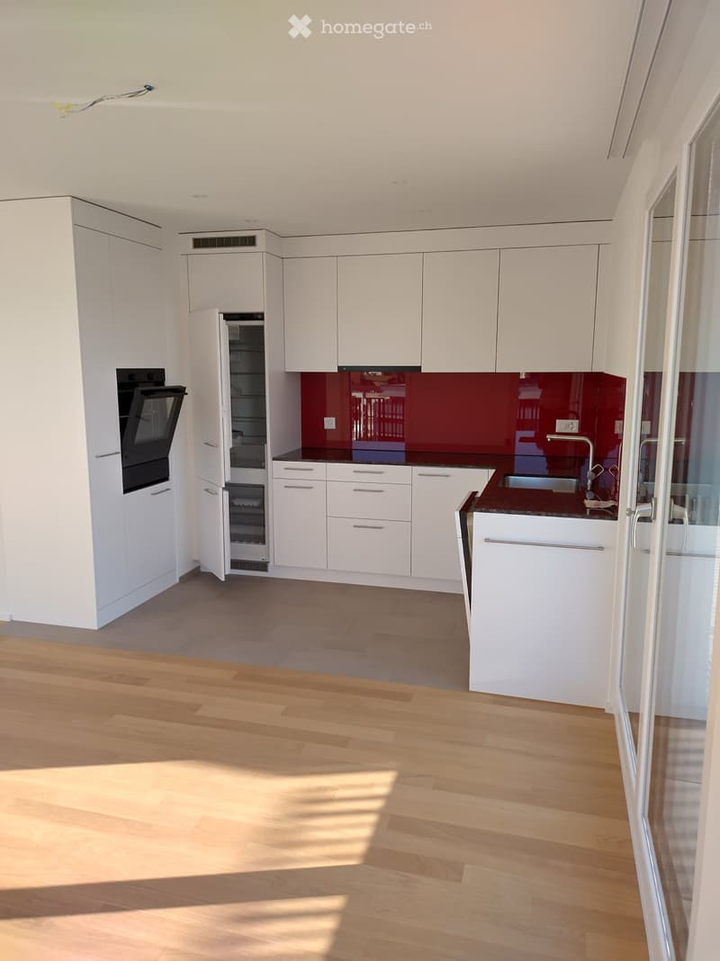 modern kitchen with white cabinetry, marble countertop, stainless steel appliances, red glass backsplash, wooden floor, sink with faucet, double oven