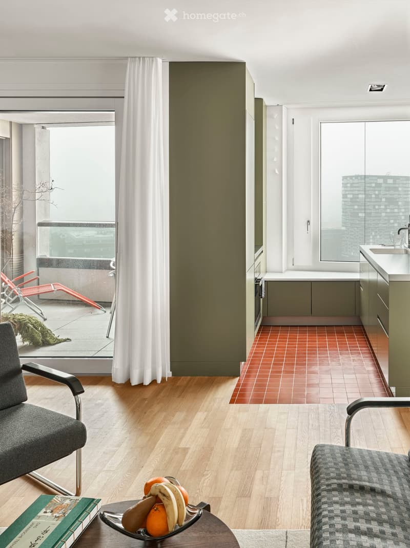 modern living room with wooden floor, large windows, balcony, modern furniture, kitchen area with red tiled floor