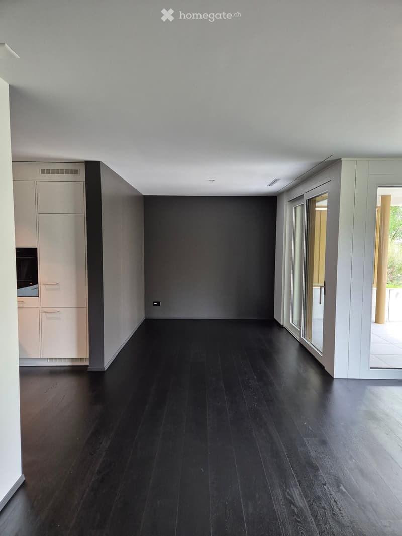 empty room, gray walls, black hardwood floors, white ceiling, sliding glass doors, and a balcony