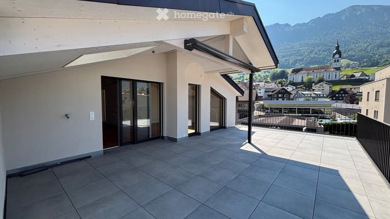 Balcony with tiled floor, glass sliding doors, metal railing, and scenic mountain view.