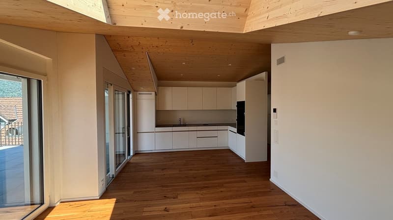 Modern kitchen with white cabinets, wooden flooring, and large glass doors leading to a balcony.