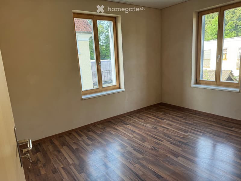 Empty room with wooden flooring and large windows, no furniture or equipment present.