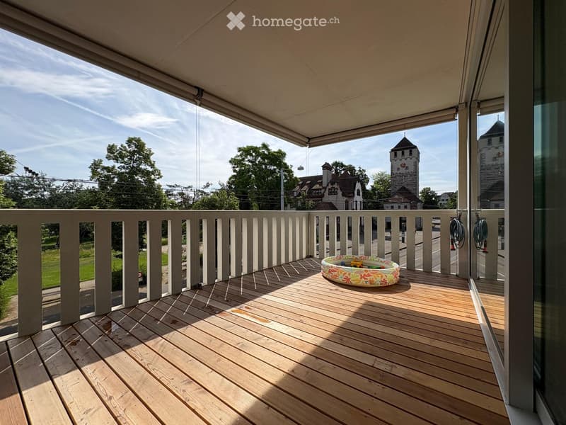 Wooden balcony with railing, retractable awning, and a small inflatable swimming pool.