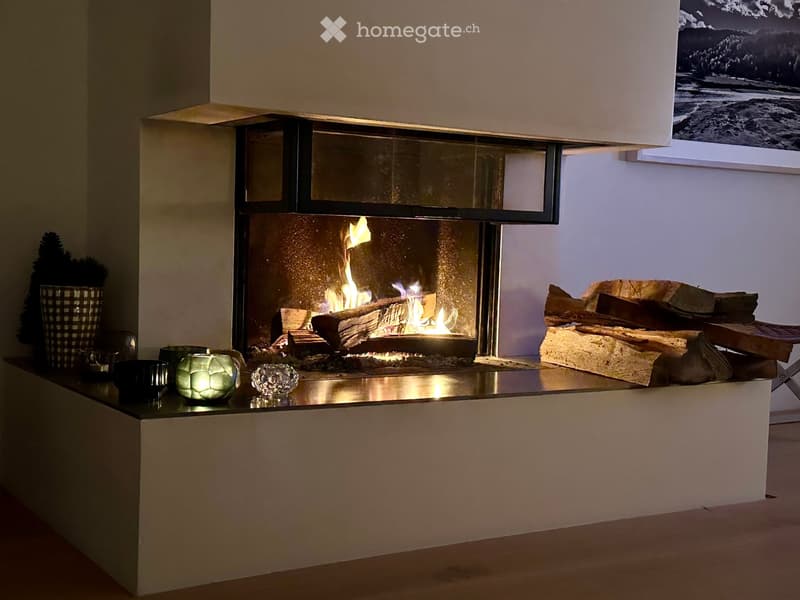 Modern living room with a sleek fireplace, wood stack, decorative vase, and crystal ornaments on the mantel.