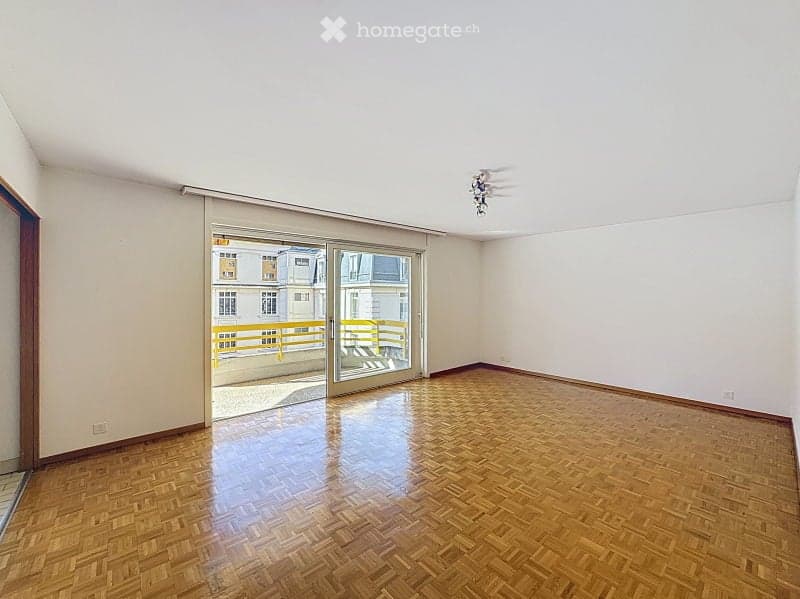 Empty room with wooden flooring, white walls, and large sliding glass doors leading to a balcony.