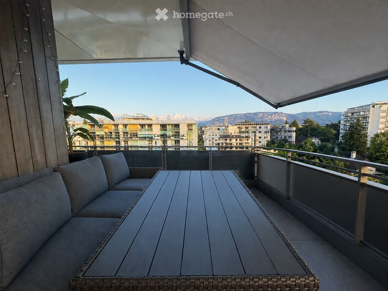 Balcony with a sofa, table, and a view of the city and mountains.