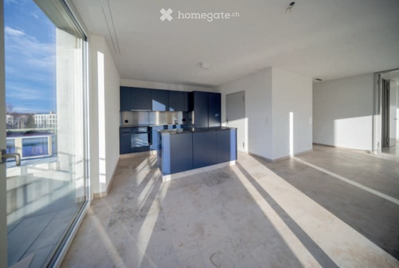 Modern kitchen with dark blue cabinets, a central island, and large windows offering a view of the balcony.
