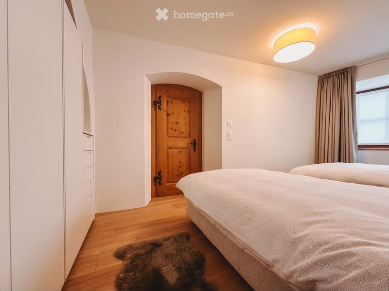 Bedroom. Cozy bedroom with two single beds, a wooden wardrobe, a fur rug, and a window with curtains.