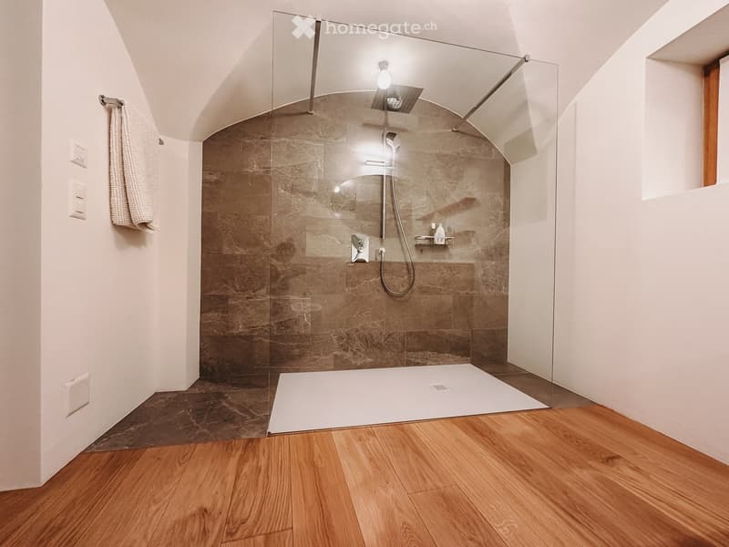 Bathroom. Modern bathroom with a glass-enclosed shower, wooden flooring, and a towel hanging on the wall.