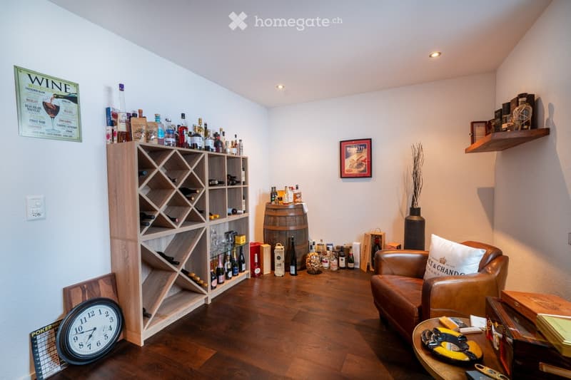 wine storage room with bottles, a chair, a wooden shelf, a desk with items, a poster on the wall