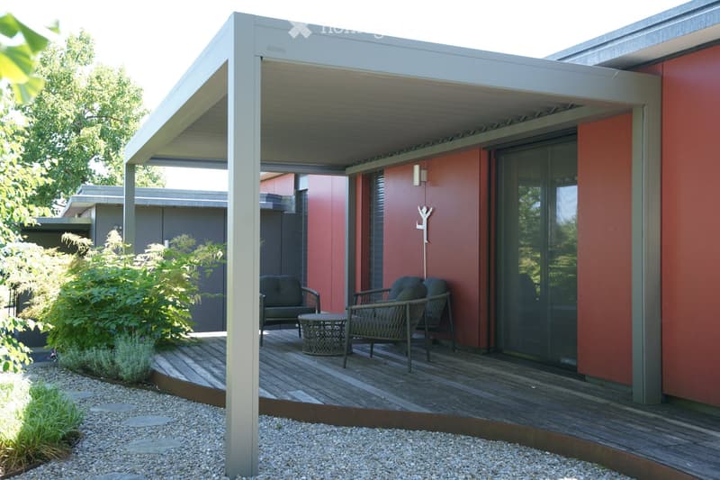 covered patio with wooden floor, metal frame, red walls, outdoor seating, table, plants