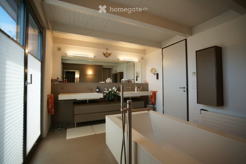 modern bathroom with double sink, large mirror, bathtub, and underfloor heating