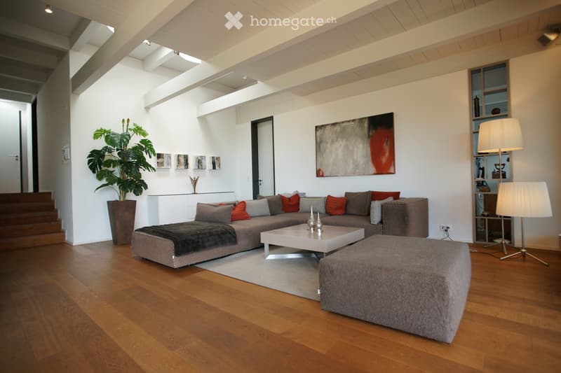 modern living room, gray sofa, white coffee table, gray ottoman, wooden floor, white walls, large painting, lamps, potted plant