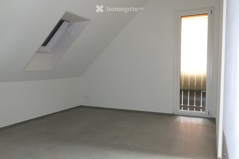 Empty room with white walls, dark tiled floor, and a large window with blinds. No furniture or equipment is present.