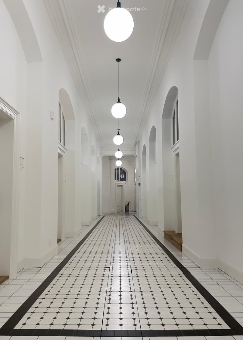 White walls, black and white tiles, arched windows, hanging globe lights