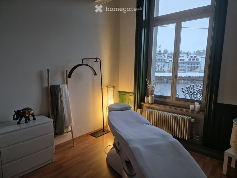 massage table, wooden floor, lamp, white cabinet, towels, radiator, decorative items, window with lake view