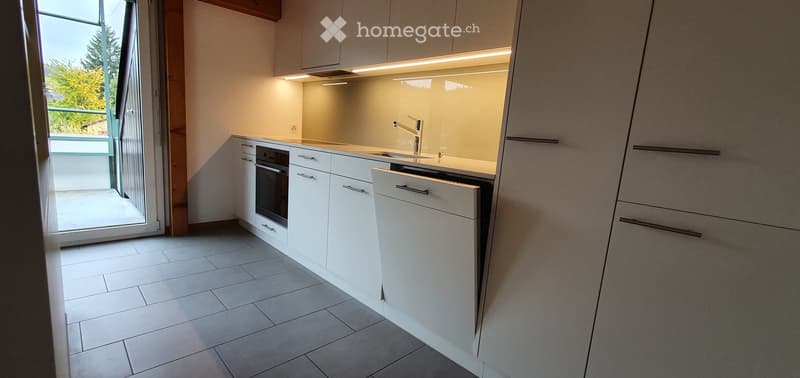 Modern kitchen with white cabinets, tiled floor, built-in oven, dishwasher, and a sink with a modern faucet.