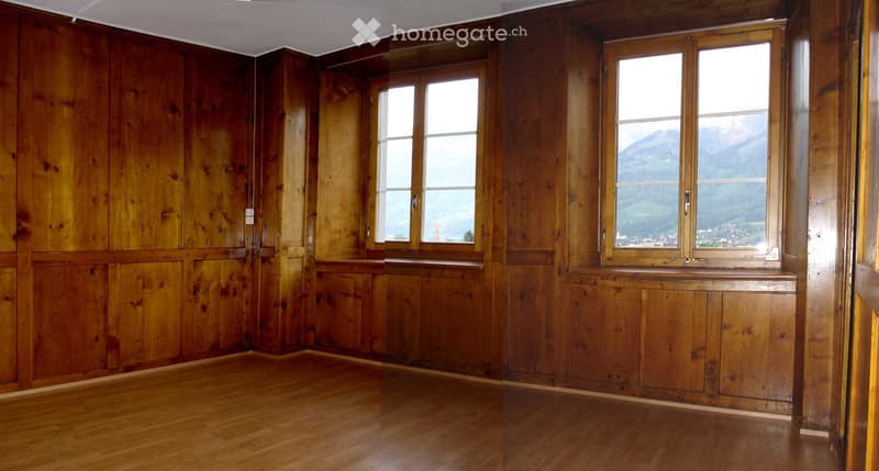 Empty room with wooden walls and floor, large windows offering a scenic mountain view.