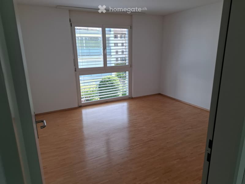 Empty room with wooden flooring, white walls, and large windows with blinds. No furniture or equipment present.