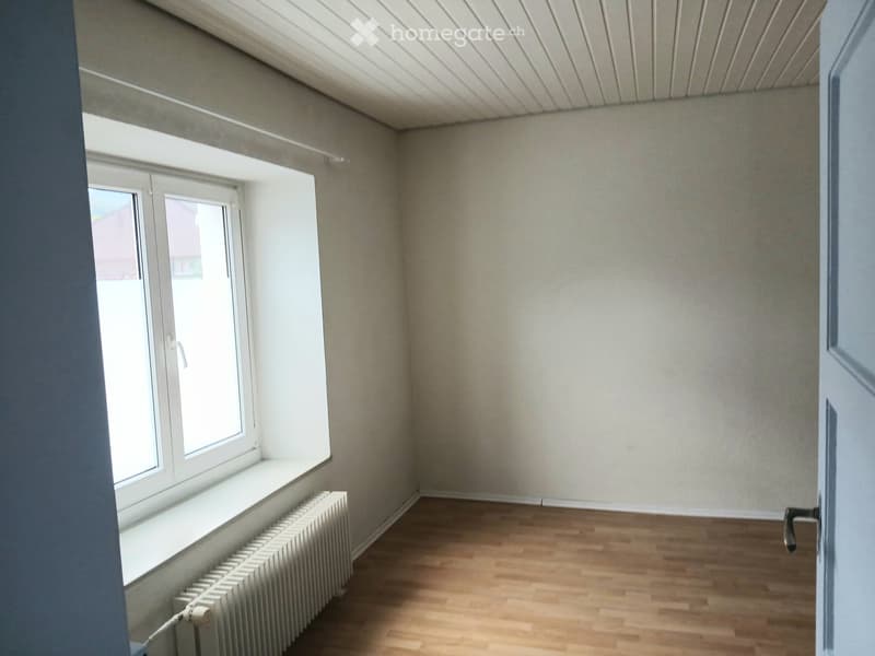 Empty room, large window, radiator, wooden floor, white walls