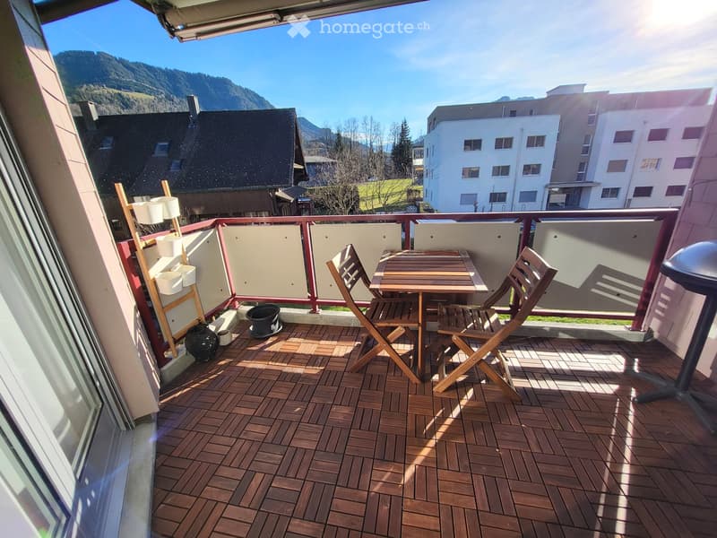 Balcony with wooden decking, small table and chairs, decorative items, and a scenic mountain view.