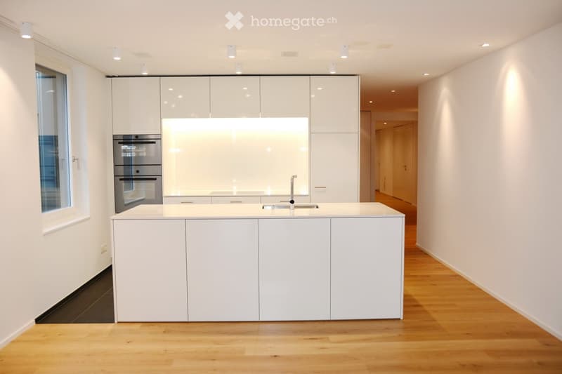 Modern kitchen with white cabinets, a central island, stainless steel appliances, and a sleek design.