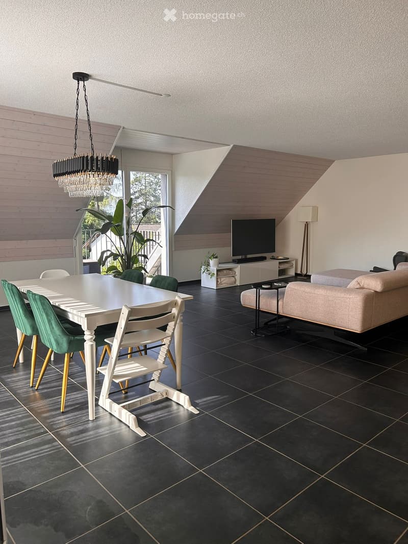 Modern living and dining area with a white dining table, green chairs, a beige sofa, a television, and a chandelier.