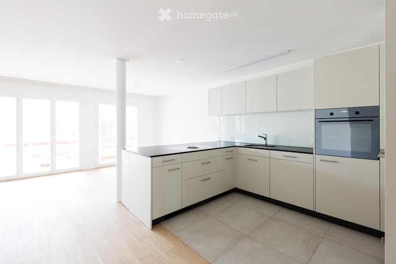 Modern kitchen with white cabinets, black countertops, and built-in appliances including an oven and sink.