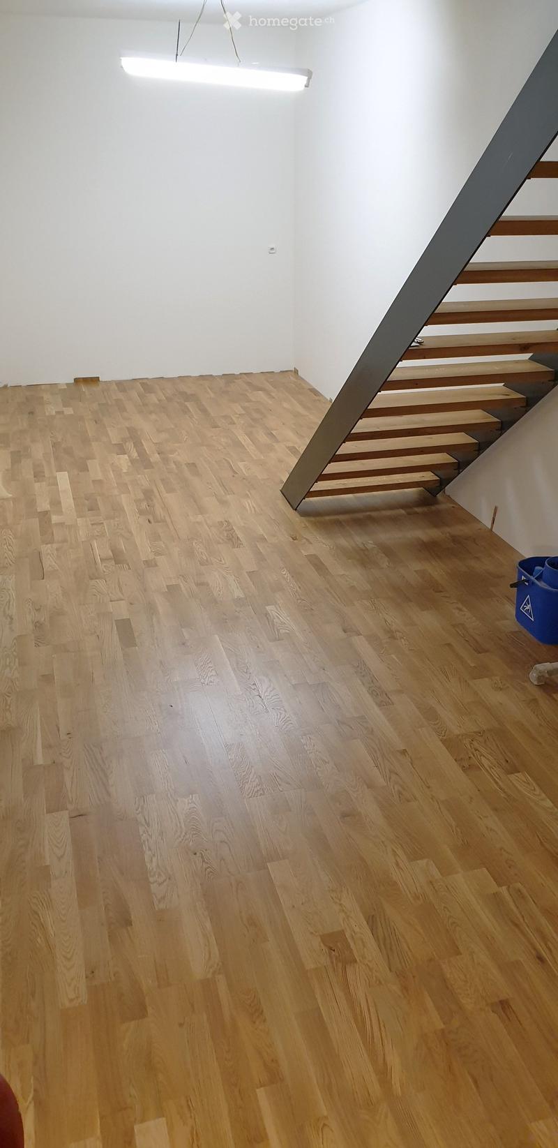 Empty room with light wooden flooring and white walls, featuring a staircase leading upwards.