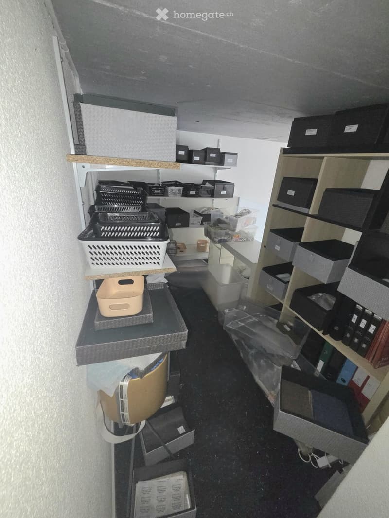 Storage room with multiple shelves and cabinets filled with boxes, bins, and other storage items.