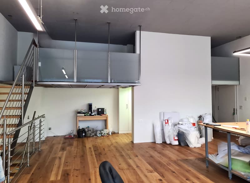 Empty room with wooden flooring, white walls, and a staircase leading to an upper level. There are some scattered items and packaging materials, but no furniture.