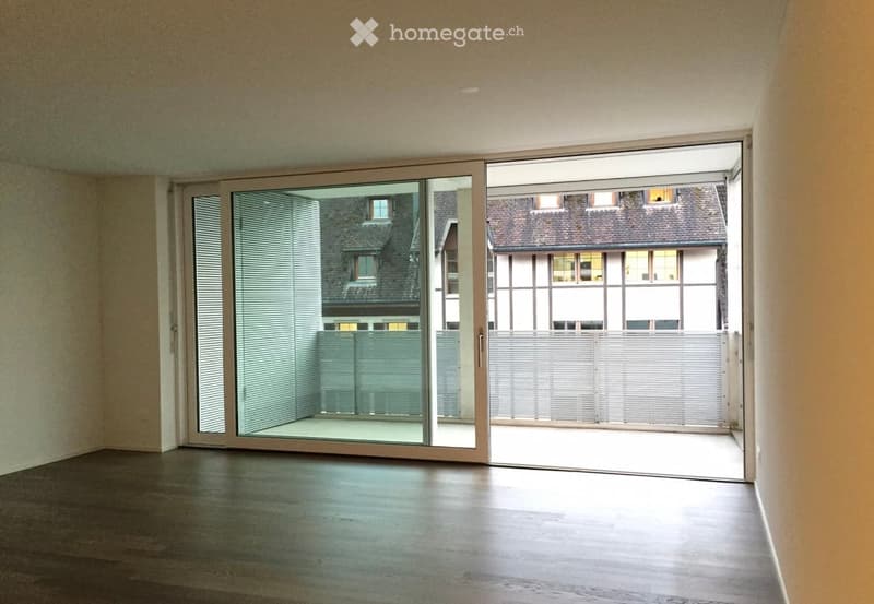 Empty room with wooden flooring and large sliding glass doors opening to a balcony or terrace area.