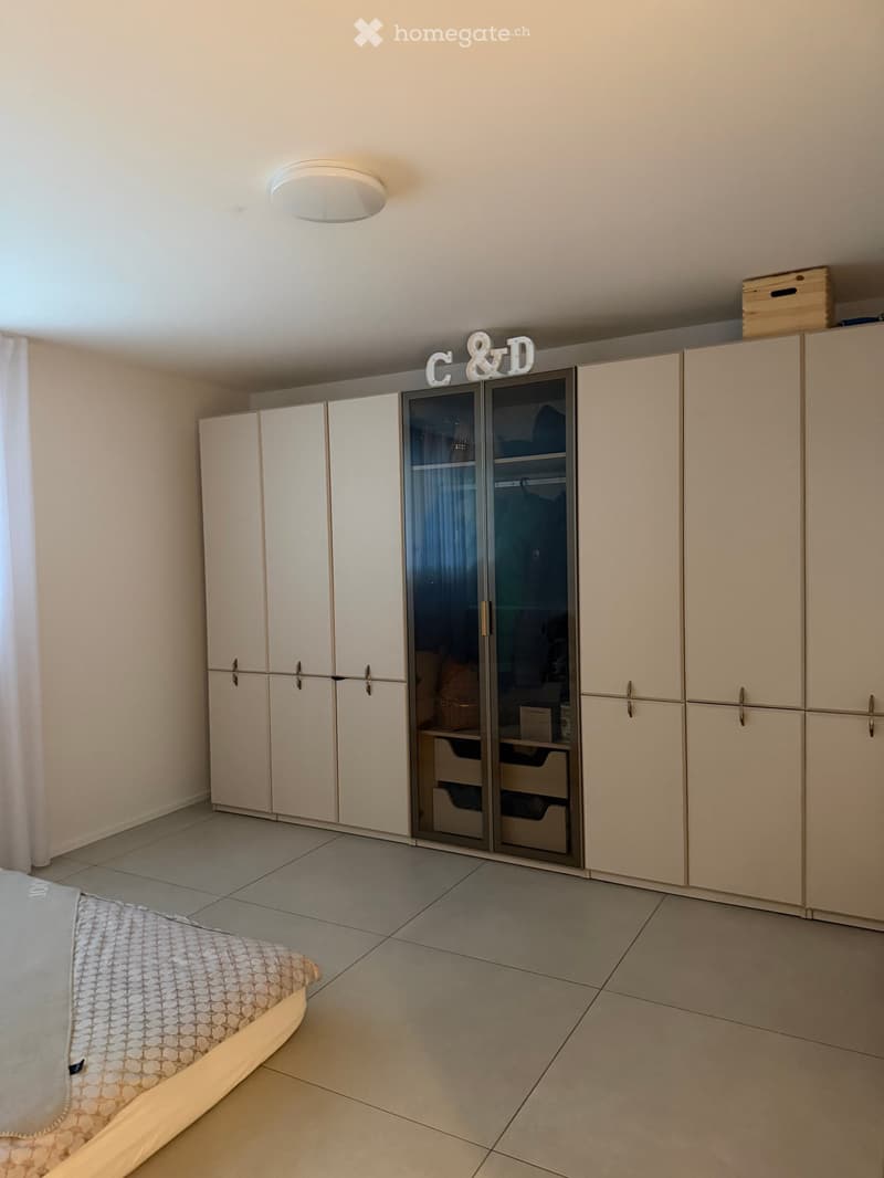 Bedroom with tiled floor, white wardrobe with mirrored doors, and a bed with patterned bedding.
