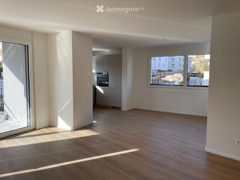 Empty room with wooden flooring, large windows, and a view of the outside. No furniture or equipment present.