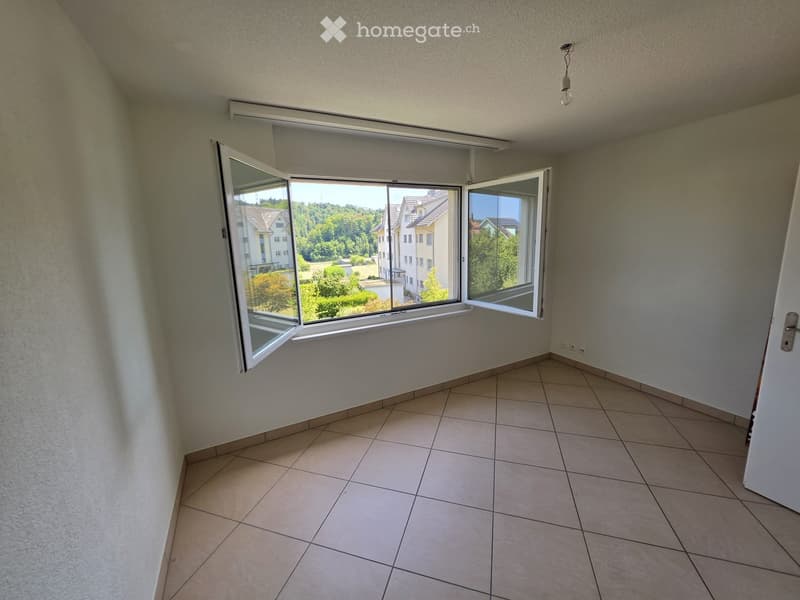 Empty room with tiled floor, large windows with blinds, and a door.