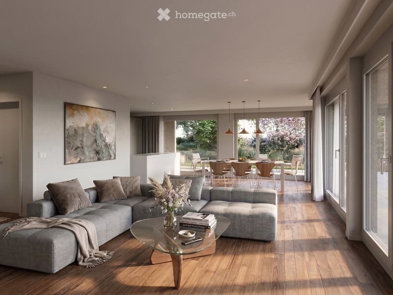 Modern living room with grey sectional sofa, glass coffee table, vase with dried flowers, books, and remote control. Open-plan layout includes a dining area with a white table and wooden chairs, large windows with views of greenery, and modern lighting fi