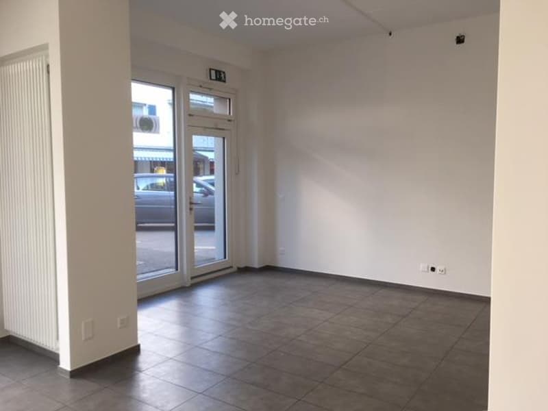 Empty room with tiled floor, white walls, large glass door leading outside, and visible electrical outlets.