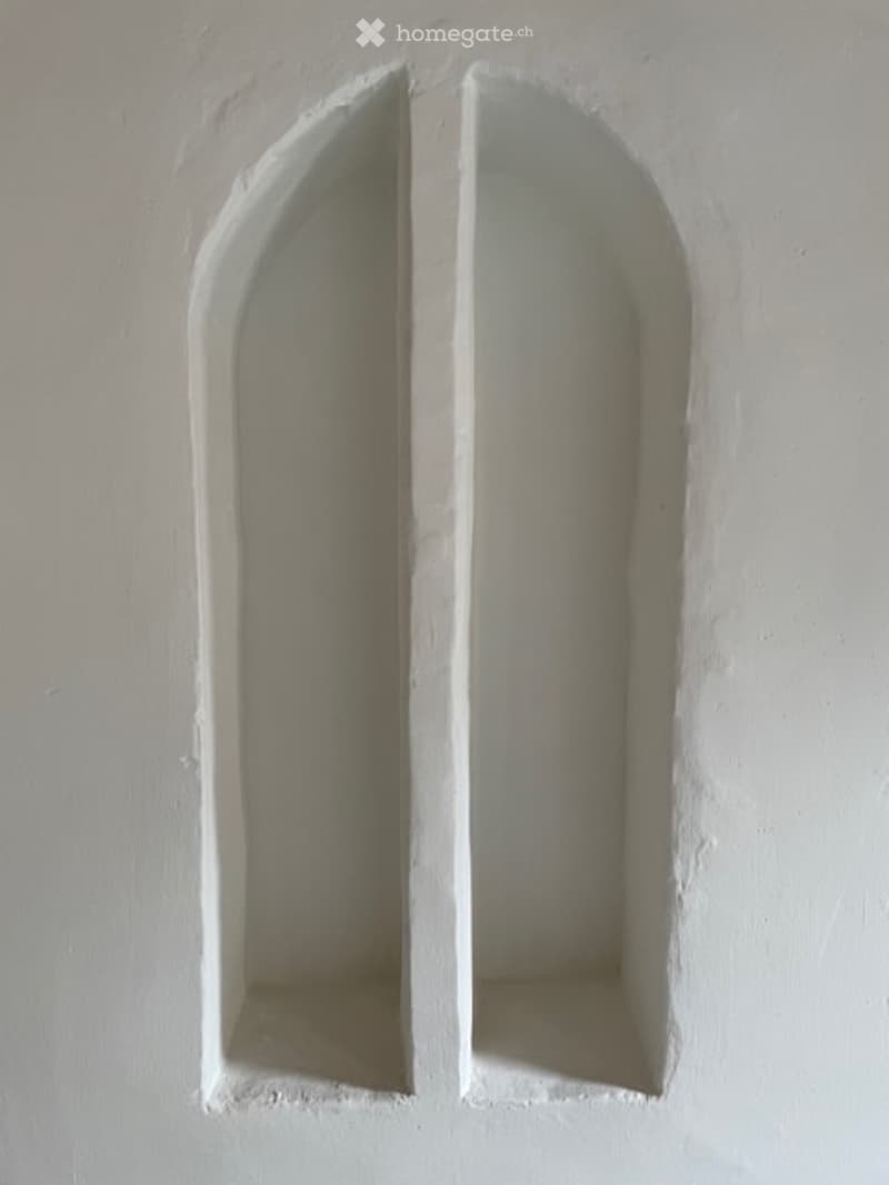 Empty room with two built-in arched niches in the wall, no furniture or items present.