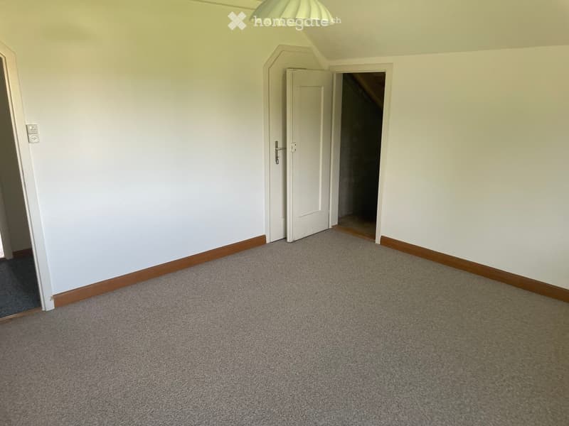 Empty room with light-colored walls, carpeted floor, and a single white door leading to another area.