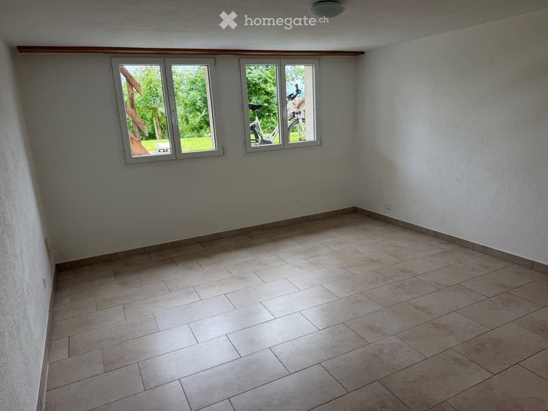 Empty room with tiled floor and large windows showing outdoor view. No furniture or equipment present.