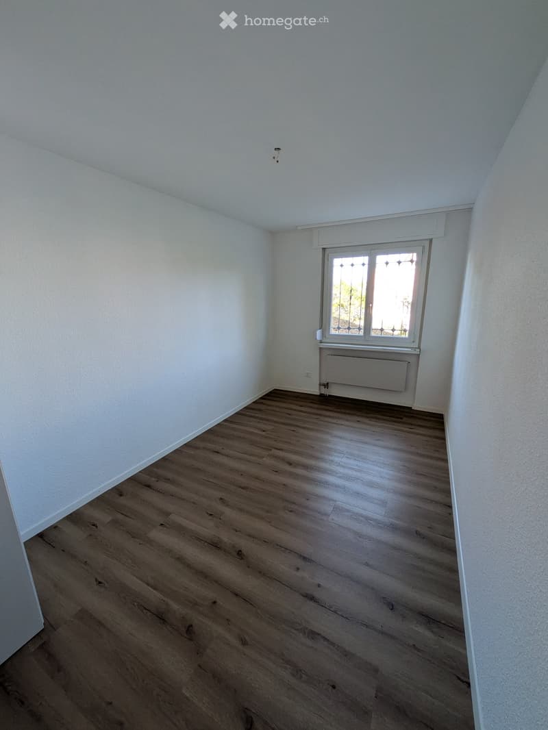 Empty room with wooden flooring, white walls, and a window with decorative glass panels. No furniture or equipment is present.