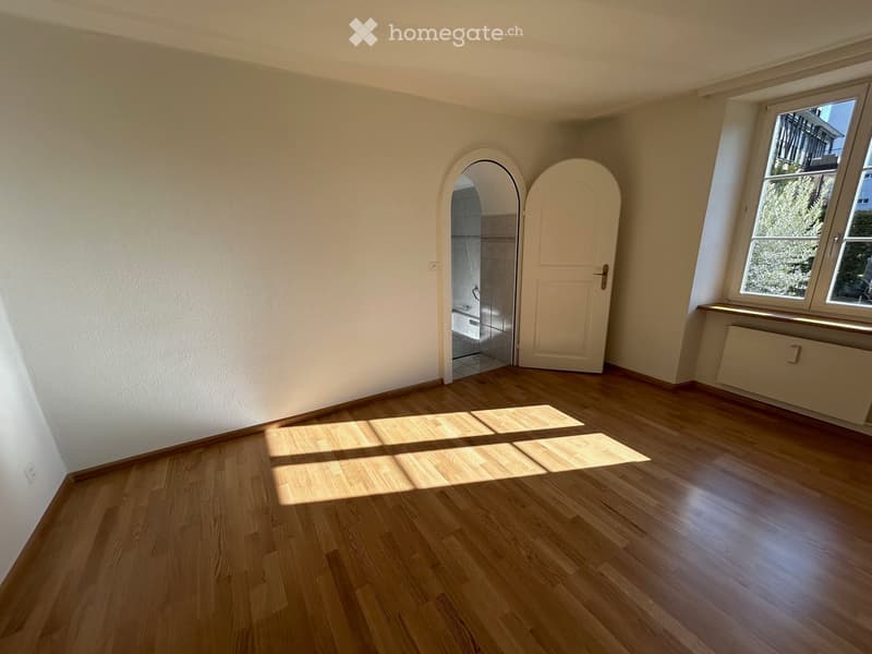 empty room, wooden floor, white walls, an open door, and a window overlooking the outside