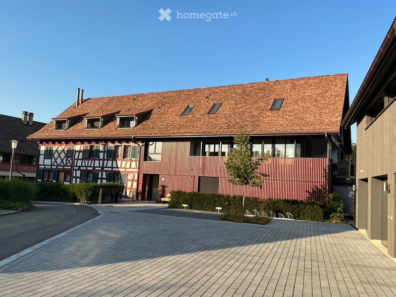 A two-story residential building with a red-tiled roof and multiple windows, featuring a mix of traditional and modern architectural elements.