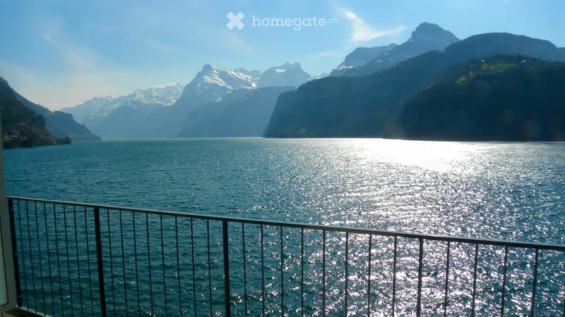 Balcony overlooking a lake with snow-capped mountains in the background.