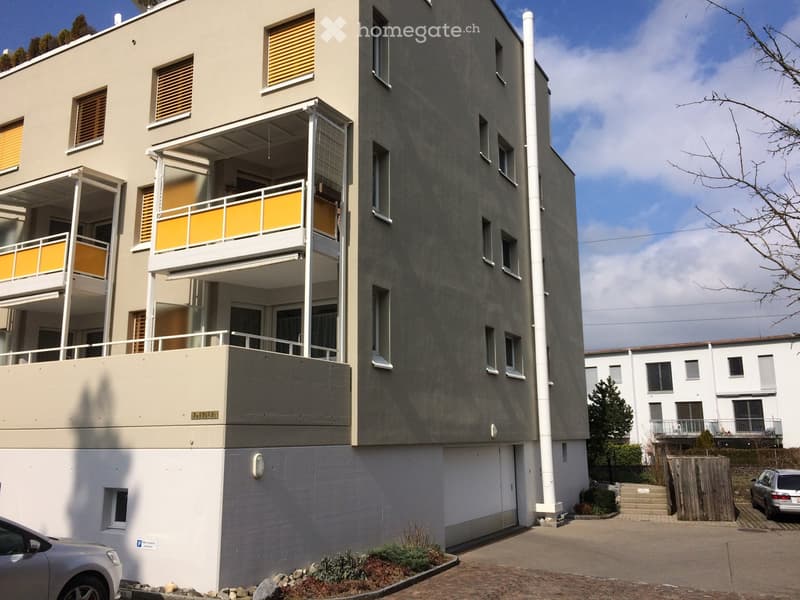 Modern multi-story residential building with balconies, large windows, and a clean, contemporary design.