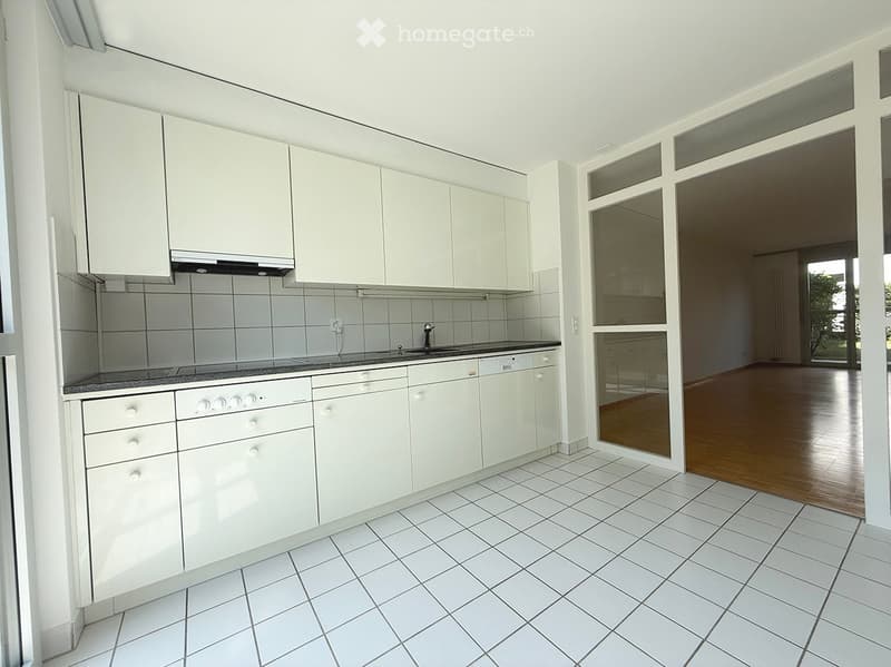 Modern kitchen with white cabinets, tiled walls, and a granite countertop. Features a sink, faucet, and oven.