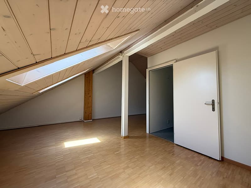 Empty attic space with wooden floors, white walls, and skylight windows. No furniture or equipment present.